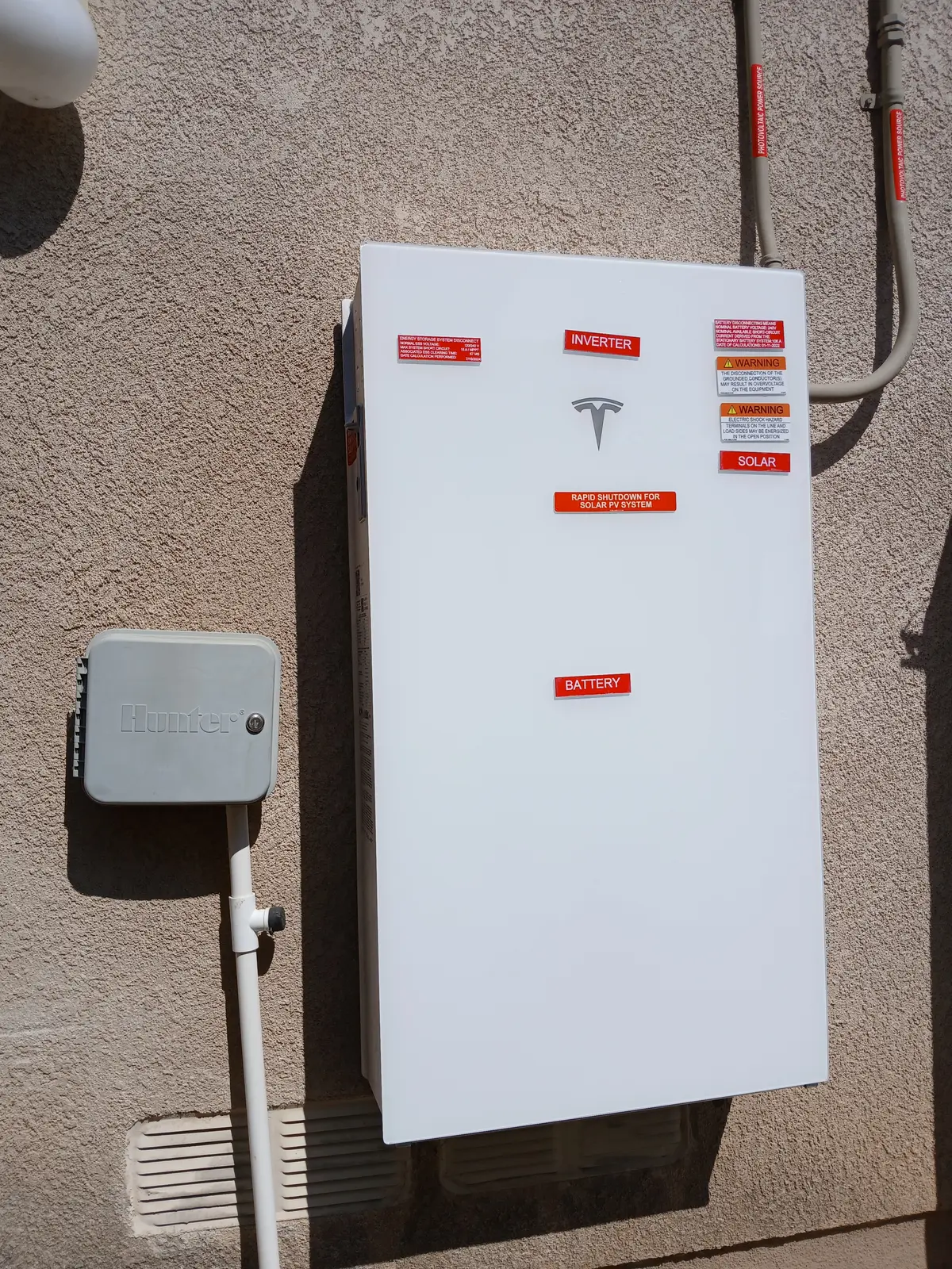 BlueWest Electric Tesla inverter and battery cabinet on stucco